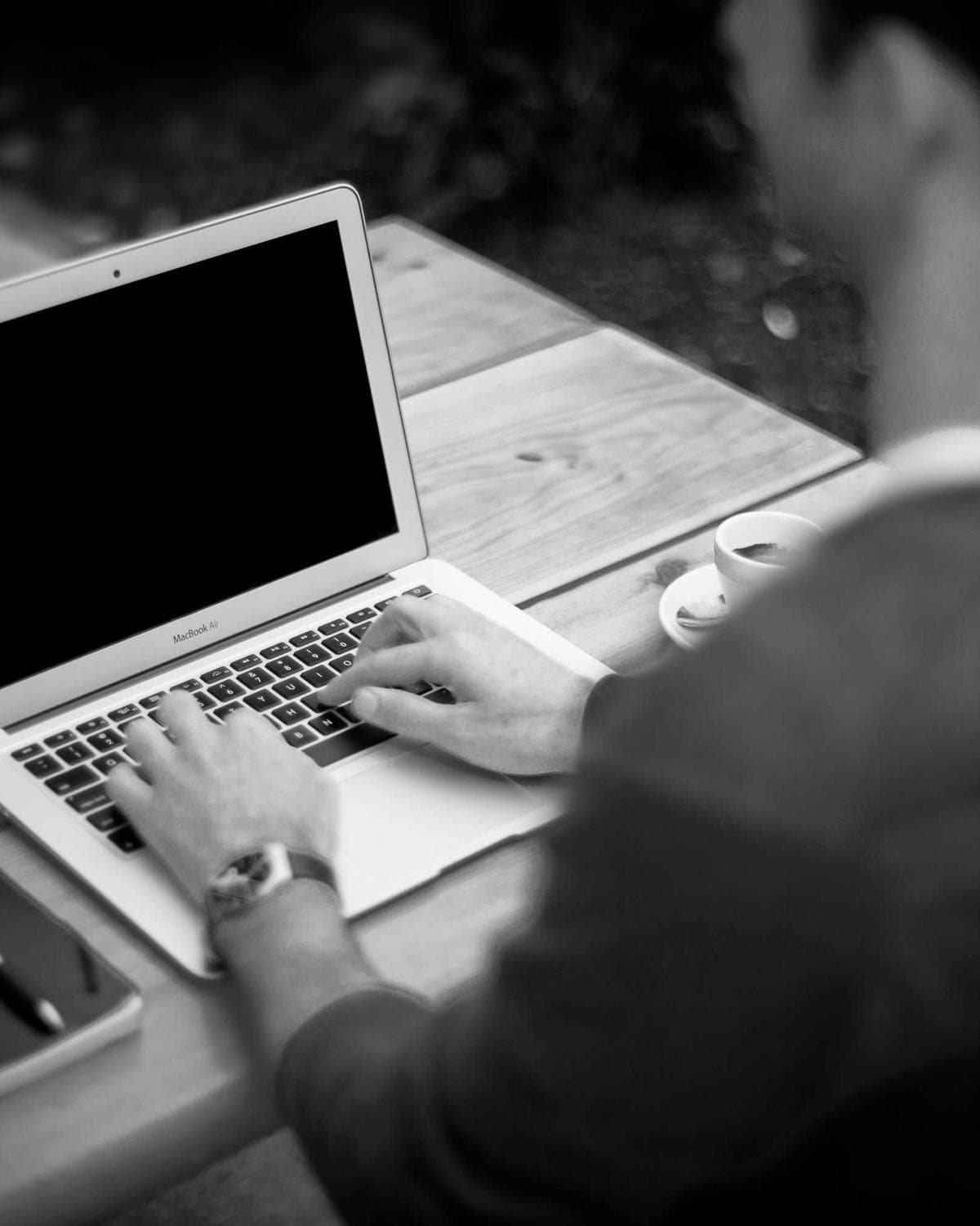 Une personne de dos, au travail devant son ordinateur portable.